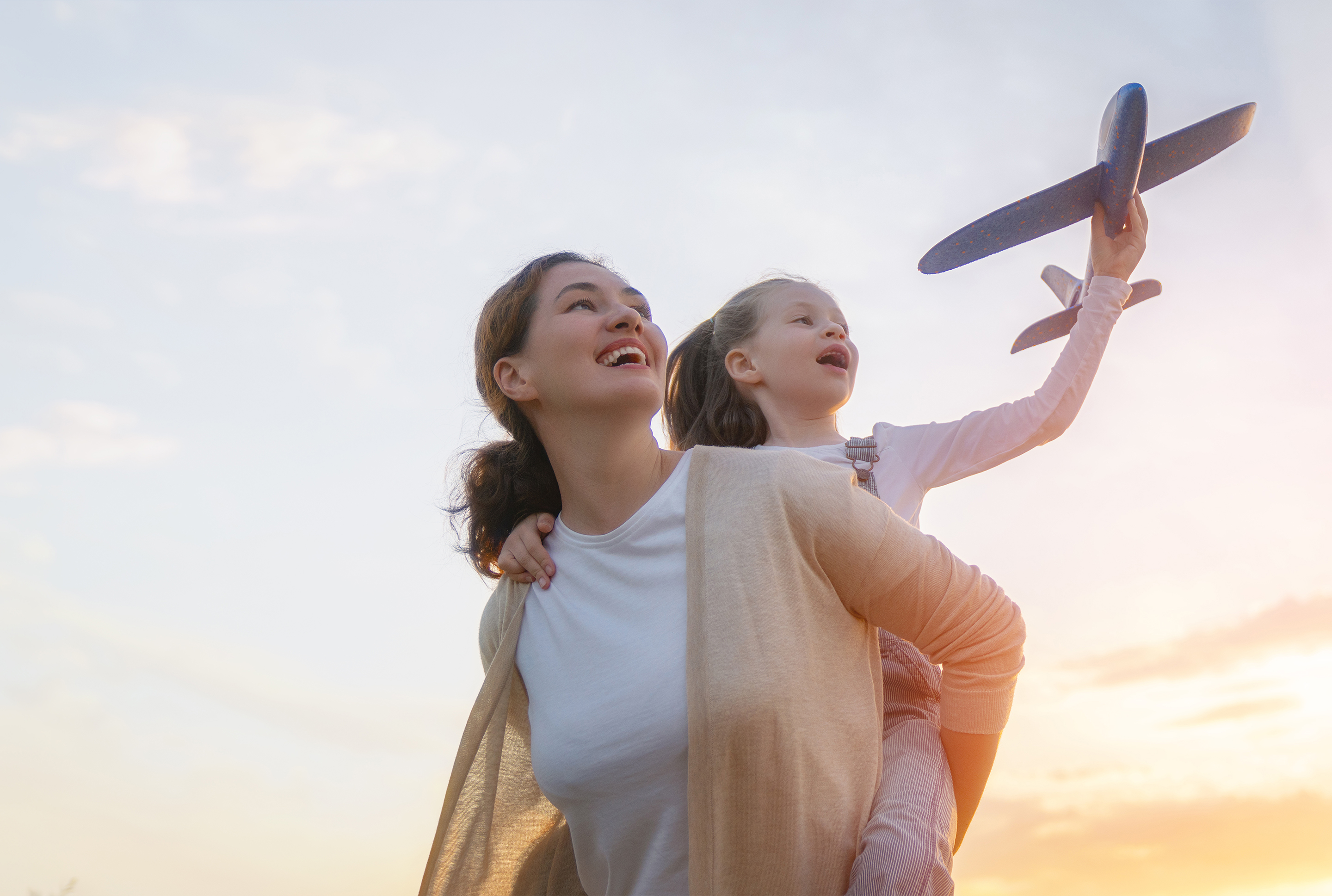 Mom and daughter outside playing with an airplane